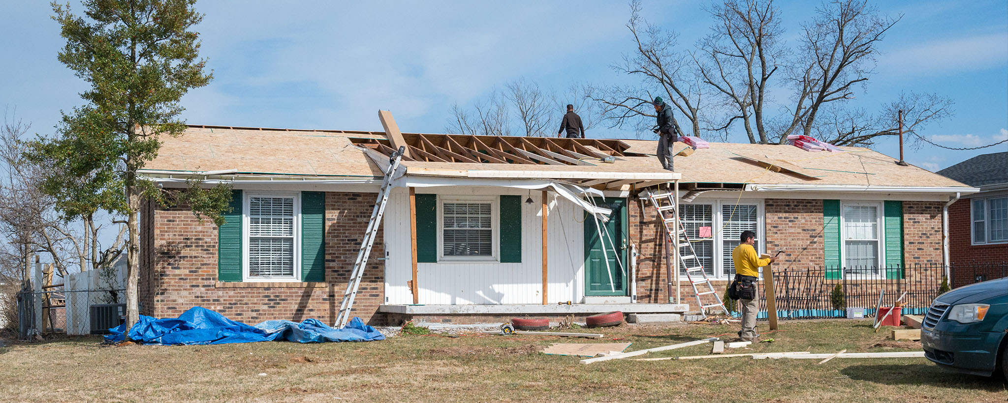 Trabajadoras reparan el techo de una casa