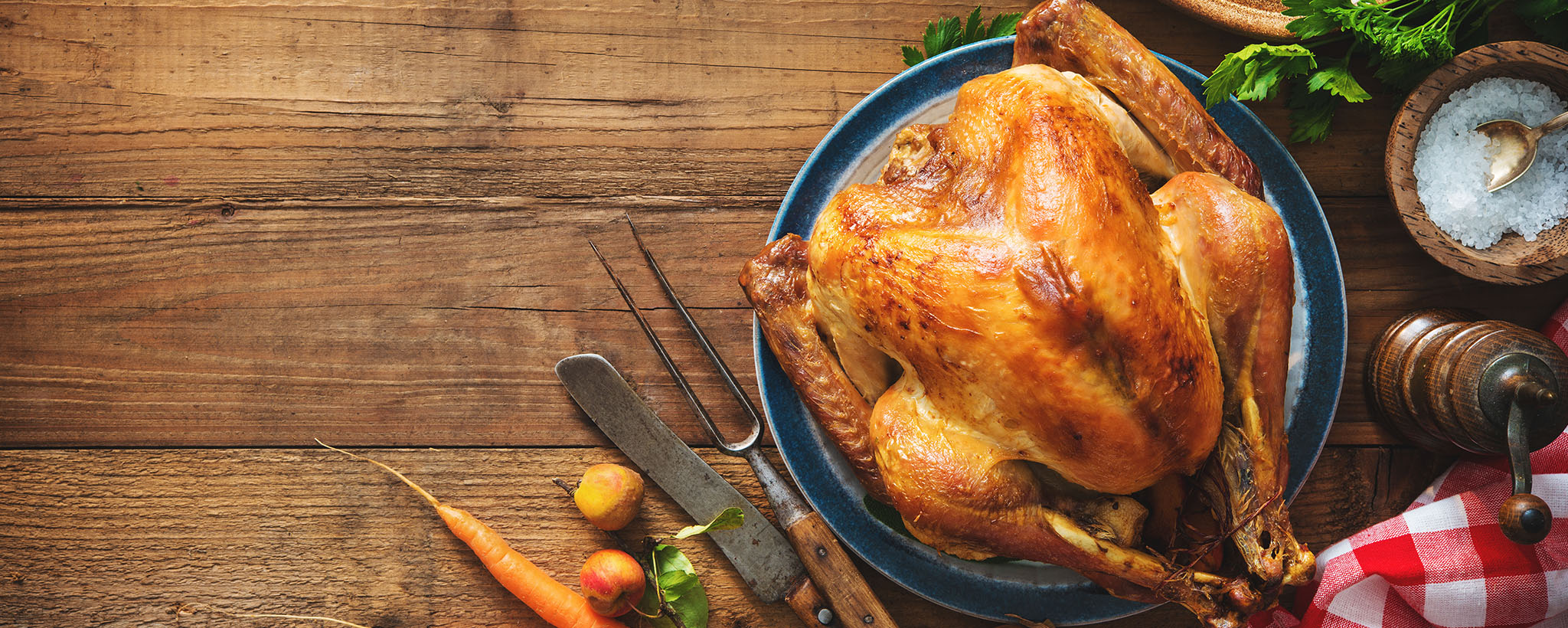 A baked thanksgiving turkey surrounded by utensils and seasonings. 