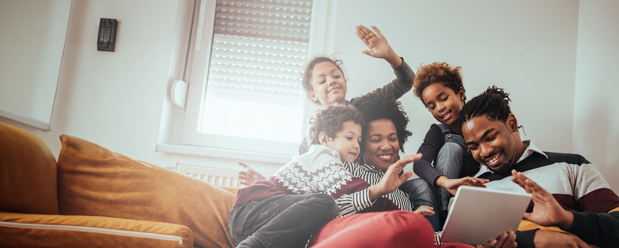 a family looks at a tablet while sitting on their couch