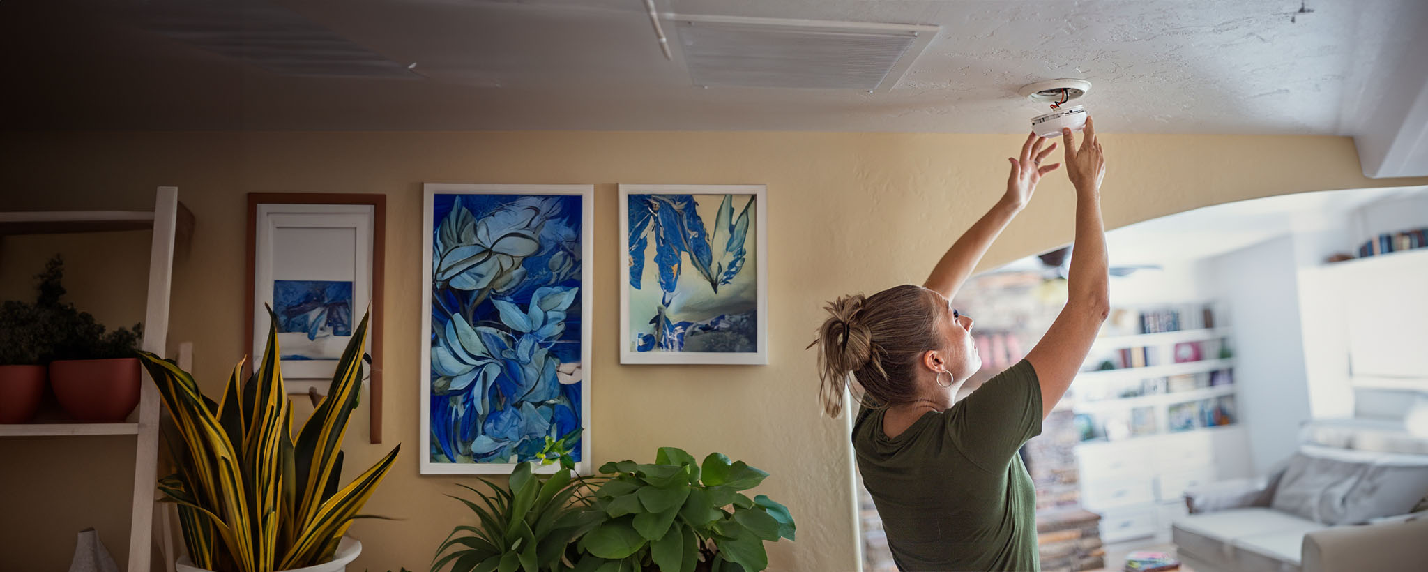 A woman checks the batteries on her smoke alarm. 