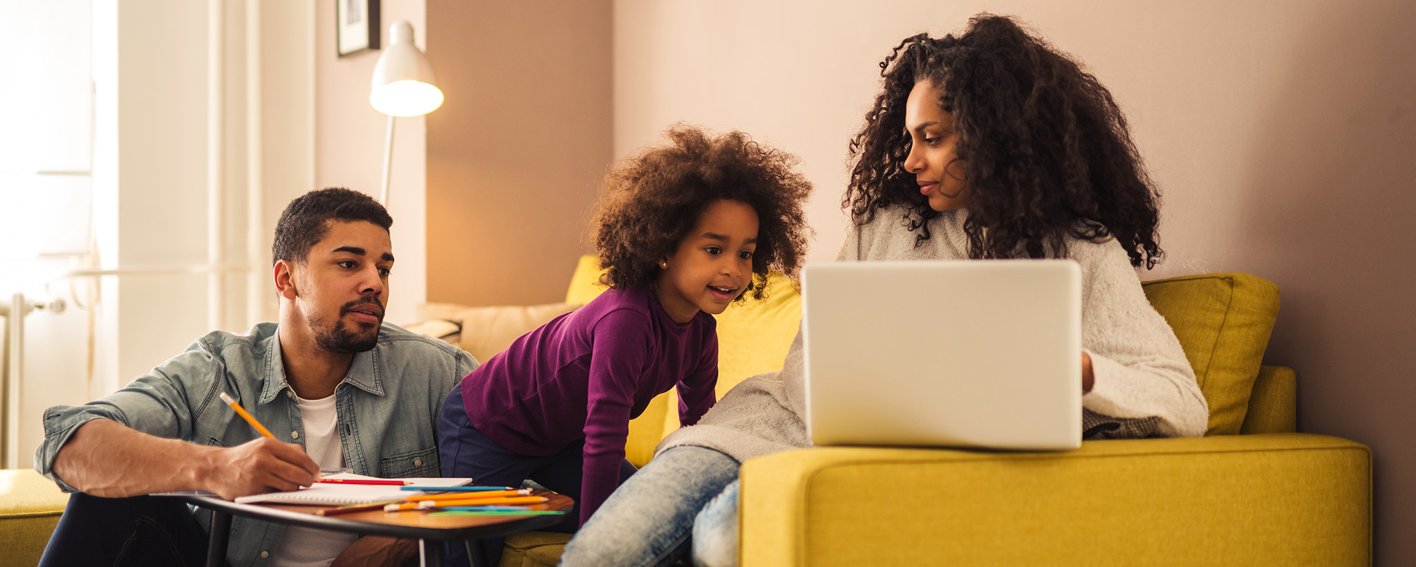 A family looks at a laptop on the couch