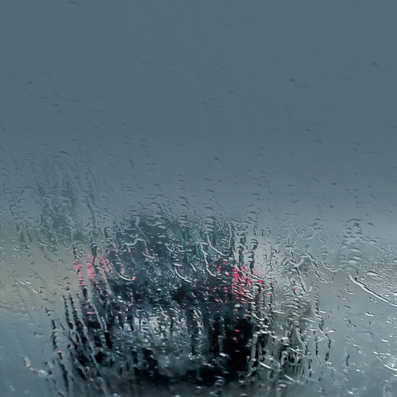 Photo of a car’s interior windshield fully wet on the outside driving during a rainstorm.