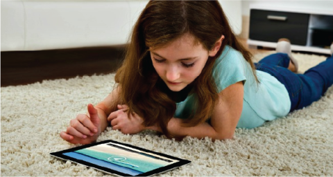 a girl laying on the floor looking at her tablet